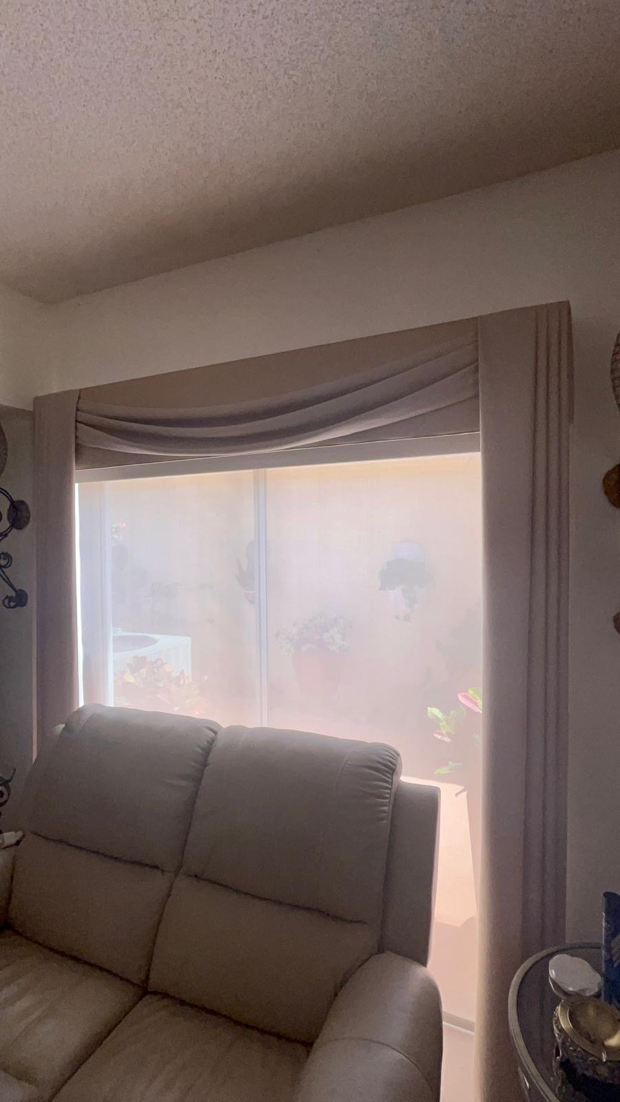 Taupe fabric drapery with a sheer layer, beside a recliner